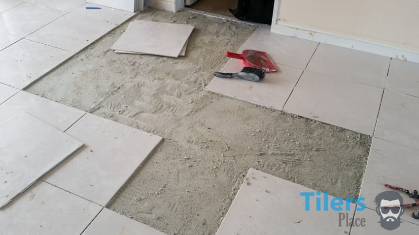These tiles could be lifted because the thinset beneath them failed due to poor surface preperation and foot traffic before the thinset cured.